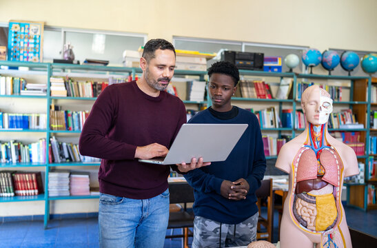 Teacher and student learning biology using laptop and anatomy model - Powered by Adobe