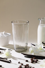 Glass cup with flowers and vanilla on gray backdrop