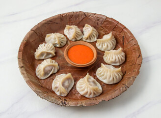 Steamed Pork Momos Served with Spicy Chili Dip on a Traditional Leaf Platter on marble background top view of dim sum