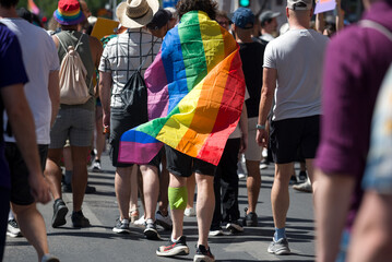 Person walking in a crowd with rainbow flag on his back