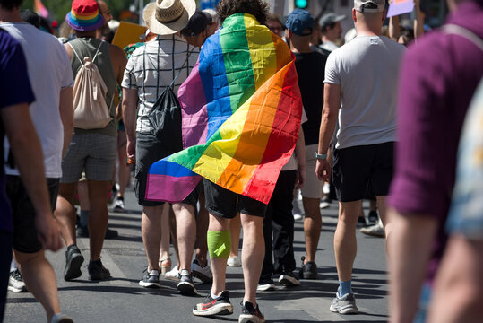 Person walking in a crowd with rainbow flag on his back