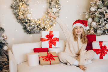 Joyful Child Celebrating Christmas on Cozy Sofa with Gifts