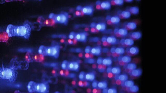 Macro with focus pull on a vibrant RGB LED display creating a soft bokeh effect from colorful light points with shifting focus revealing the diode matrix against a dark electronic surface.