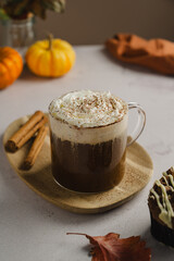 Pumpkin spice latte in glass mug with whipped cream and cinnamon, autumn hot drink