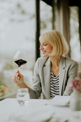 Enjoying a fine glass of red wine while seated in a stylish restaurant during a sunny afternoon