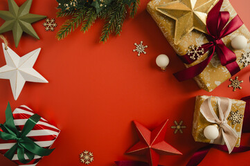 Christmas flat lay frame, composition with gifts boxes and festive stars and baubles over red background