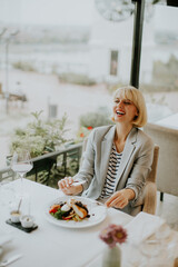 Woman enjoying a delightful meal in a modern restaurant by the waterfront during a sunny day