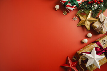 Christmas flat lay frame, composition with gifts boxes and festive stars and baubles over red background