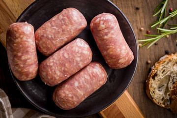 Photo of italian sausage salsiccia on plate on wooden table. Top view.