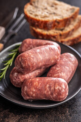Photo of italian sausage salsiccia on plate on black table.