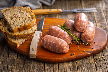 Photo of italian sausage salsiccia on cutting board on wooden table.