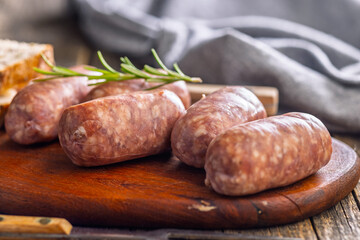 Photo of italian sausage salsiccia on cutting board on wooden table.