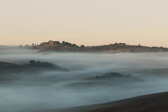 Tuscan countryside with farmhouses and morning fog over hills - Powered by Adobe
