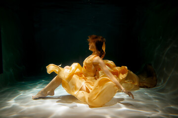 An Elegant Underwater Dance Exquisite in Ethereal Yellow Fabric Captivates the Eye of Viewers