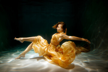 An ethereal underwater dance performance featuring a graceful dancer in stunning golden fabric © diczman