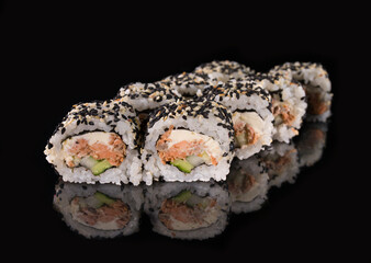 Uramaki rolls with seared salmon, Philadelphia cheese, and avocado topped with sesame seeds on a reflective surface