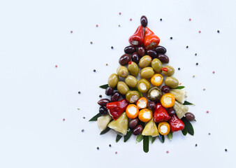 Creative Christmas tree made of Greek olives, peppers, and cheese appetizers on white background. Festive Mediterranean food composition, healthy holiday snack, top view.