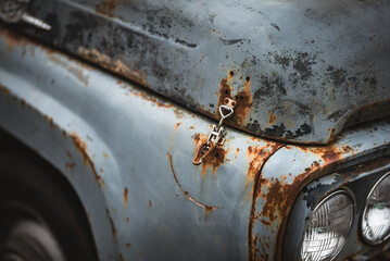 A detailed shot of a weathered, vintage car hood with visible rust and latch.
