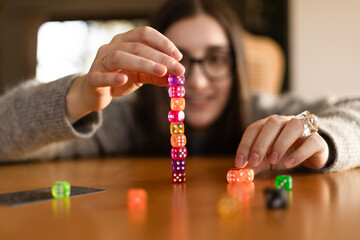Colorful dice falling and scattering on the table in front of a young woman. Fun and dynamic play...