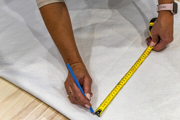 Measuring white boucl&eacute; fabric with scissors and pencil for DIY sofa cover