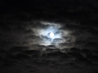 The bright light of a supermoon, peeking through the cloudy, dark sky, highlighting the clouds. November, Beaver Moon. Skies above the Blackwater National Wildlife Refuge, Dorchester County, Maryland.