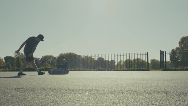 A skateboarder doing tricks in slow motion in a basketball pitch in the sunset