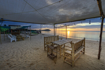 Beach scene with a large tent and several tables and chairs