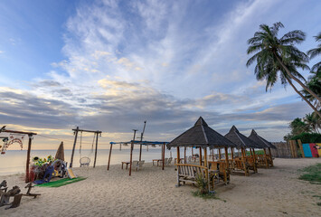 Beach with a few small huts and a few people sitting on the beach