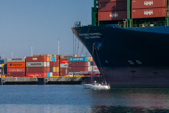 Cargo ship and sailboat at the Port of Oakland illustrate global trade on the West Coast