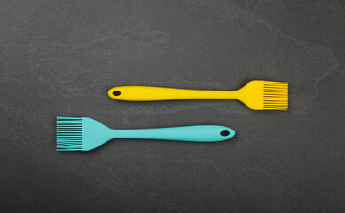 Two silicone culinary brushes on black slate board
