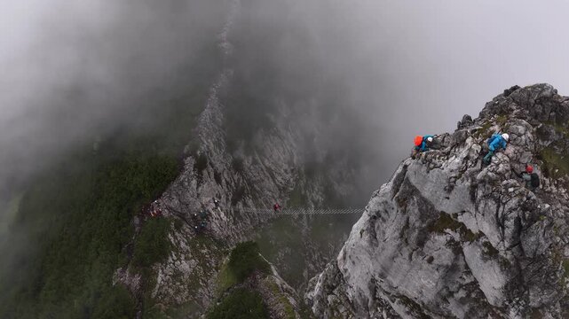 Aerial view of mountaineers climbing a steep ridge in foggy conditions, Dachstein, Austria