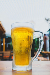 50 cl pint of beer served on wooden surface. Cold beer glass on wooden table. Refreshing golden beer in glass on wooden table. Full glass of lager beer on wooden table.
