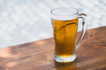 50 cl pint of beer served on wooden surface. Cold beer glass on wooden table. Refreshing golden beer in glass on wooden table. Full glass of lager beer on wooden table.