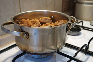 Cooking. The saucepan is on the gas stove. Meat is stewing
