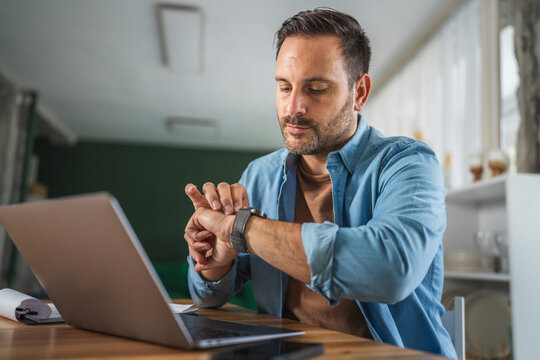 Man using smart watch checking time working with laptop - Powered by Adobe