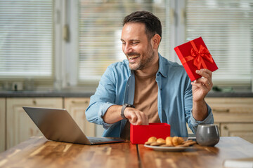 Happy man celebrating birthday on video call receiving gift
