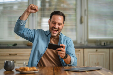 Fototapeta premium Man winning online game on smart phone celebrating success