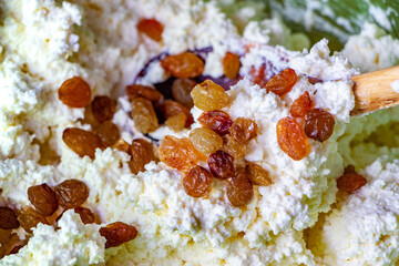 Creamy cottage cheese mixed with golden raisins and a wooden spoon, showcasing a delicious and nutritious dairy dish perfect for healthy eating and culinary creativity