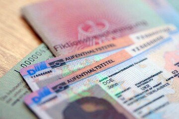 German Permanent resident card and document specimen lies on wooden table close up. Aufenthaltstitel and Fiktionsbescheinigung
