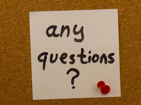 Handwritten note with the phrase any questions pinned to a corkboard