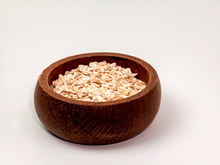 Rolled oats in a wooden bowl on a white background