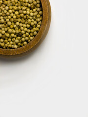 Top view of white peppercorns in a wooden bowl with copy space