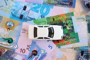Kuwaiti dinar currency money bills and toy car close up. The concept of car ownership