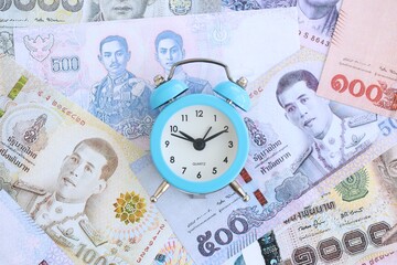 Thai baht currency money bills and alarm clock close up. The concept of time management and income