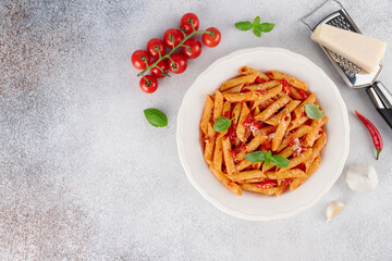 Arrabbiata pasta with tomato sauce, chili, parmesan basil on gray background. Top view. Copy space