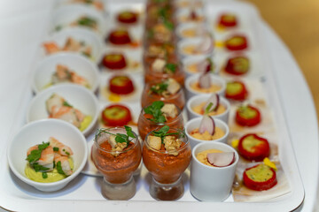 assorted gourmet appetizers served in elegant bowls and glasses on a banquet table, featuring shrimp, vegetables, and garnishes, captured with shallow depth of field in a fine dining setting.