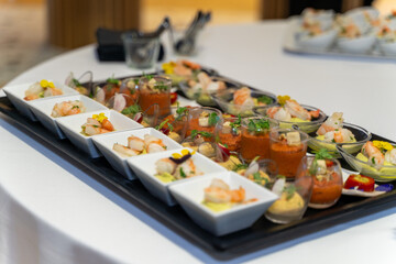 assorted gourmet appetizers served in elegant bowls and glasses on a banquet table, featuring shrimp, vegetables, and garnishes, captured with shallow depth of field in a fine dining setting.