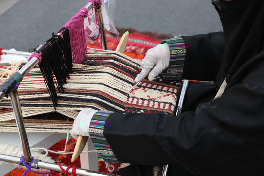 Traditional hand weaving craft in Saudi Arabia showing a woman artisan creating patterned fabric using the Al Sadu technique, reflecting cultural heritage and authentic Arabian craftsmanship.