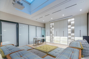 A well-designed living room features comfortable seating and bright lighting from a skylight. The space combines modern aesthetics with functional design elements, creating a cozy atmosphere.