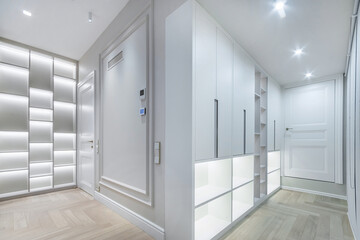 This hallway features sleek storage solutions and bright, inviting lighting. The minimalist design creates a spacious feel, enhancing the modern aesthetic of the home.